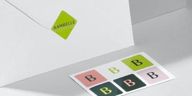 Enveloppe blanche fermée par un autocollant carré vert et une feuille d'autocollants de 6 mini autocollants avec logo